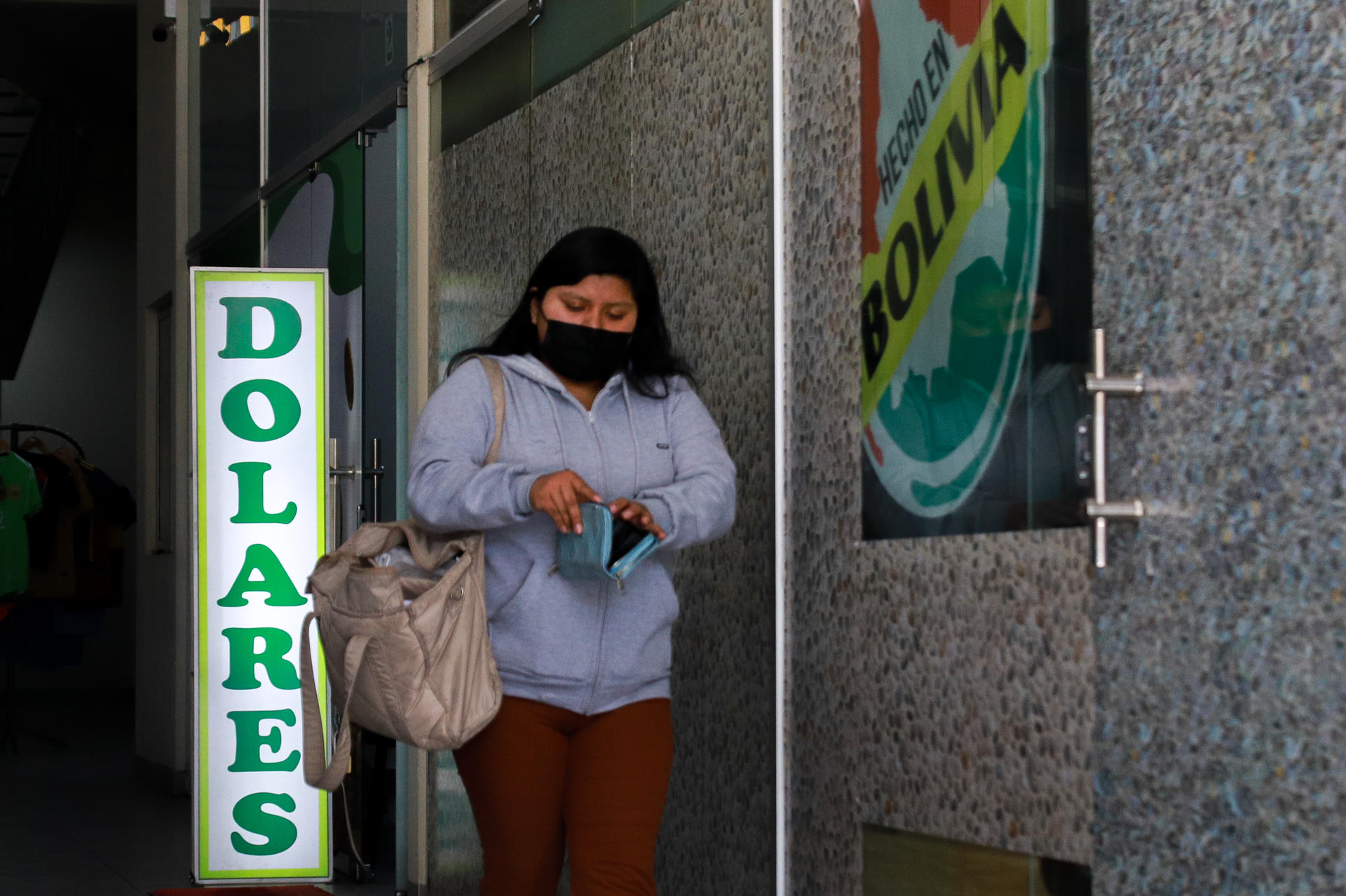 Una mujer sale de una casa de cambio este jueves, en el centro de La Paz (Bolivia). EFE/ Gabriel Márquez