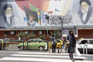 Ciudadanos iraníes caminan junto a un cartel que representa al líder supremo de Irán, ayatolá Ali Jamenei, junto al fallecido ayatolá Ruhola Jomeini en una calle de Teherán, Irán, el 13 de junio del 2013. EFE/Abedin Taherkenareh