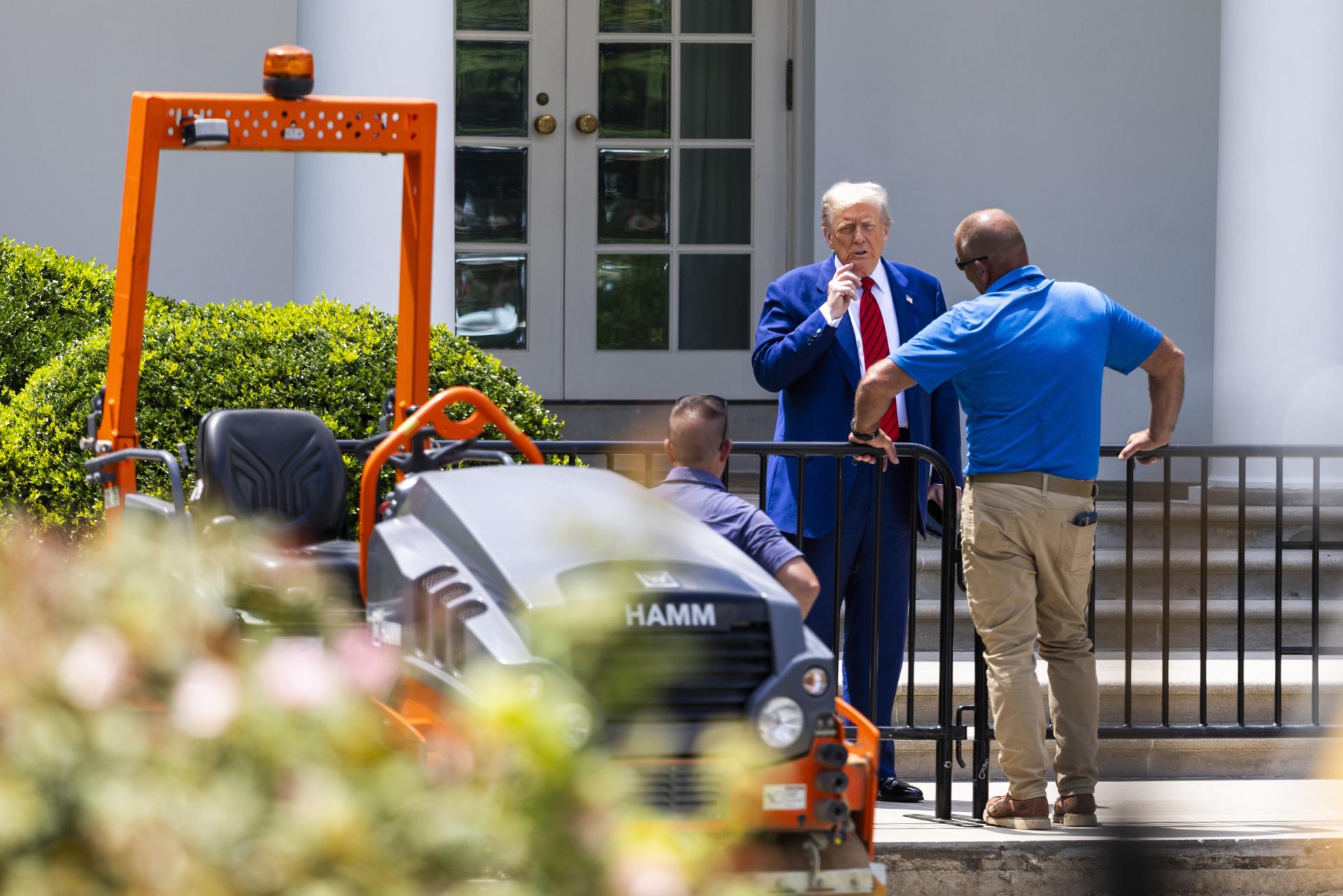El presidente de Estados Unidos, Donald Trump, habla con los trabajadores que están pavimentando el jardín de rosas de la Casa Blanca. EFE/Jim Lo Scalzo