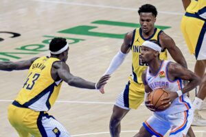 Shai Gilgeous-Alexander (d) de los Oklahoma City Thunder se prepara para lanzar ante la marca de  Bennedict Mathurin (c) y Pascal Siakam (i) de los Indiana Pacers. EFE/Manuela Soldi
