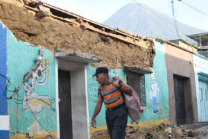 Una persona camina este miércoles cerca de los escombros ocasionados tras los fuertes temblores, en Palín (Guatemala). EFE/Alex Cruz