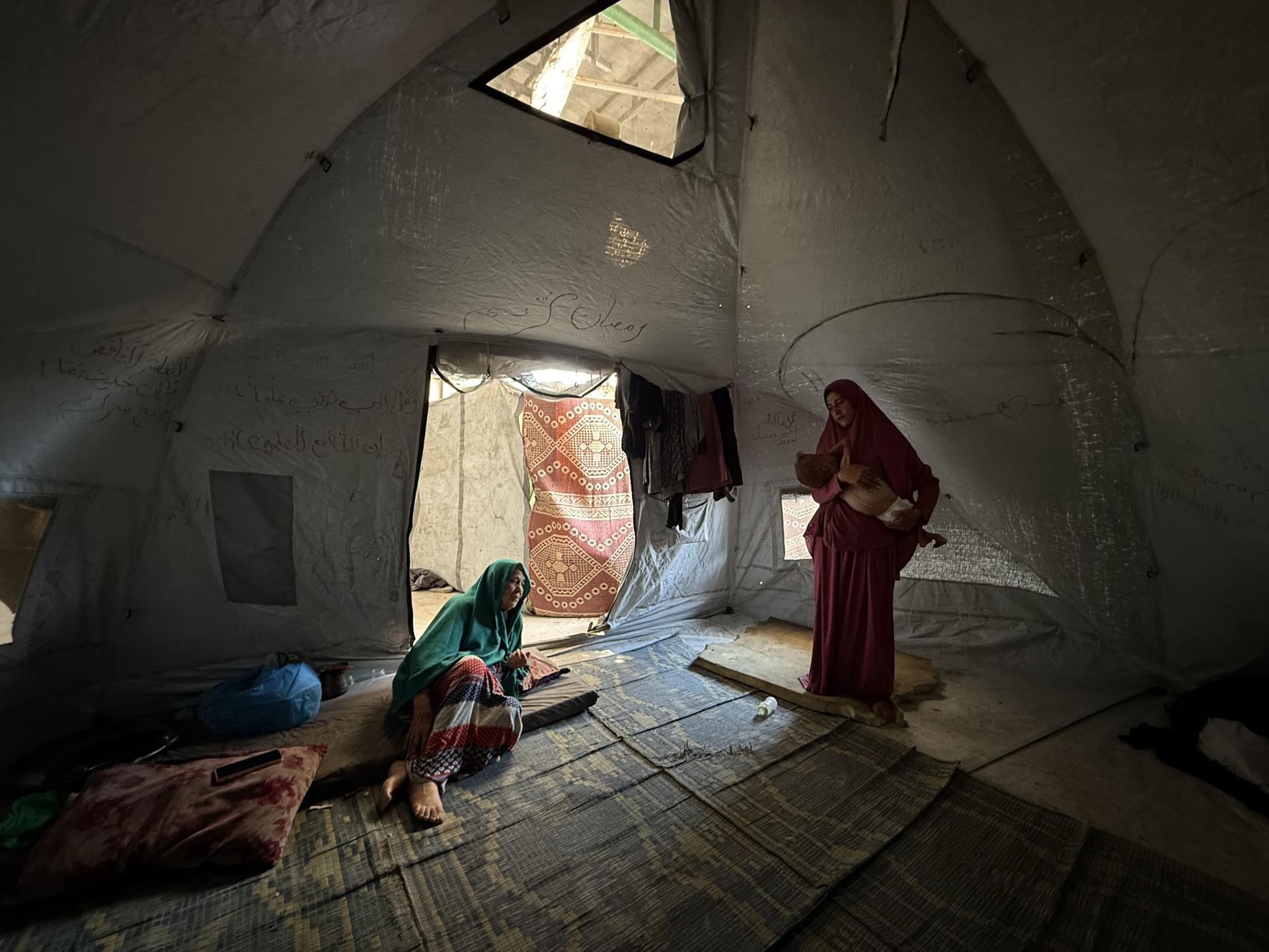 El pequeño gazatí Mohamed Motawaq, de tan solo 18 meses, de cuerpo esquelético pasa los días en Gaza en brazos de su madre, Hidaya (d), un mujer viuda, de 30 años, sin apenas leche y otros productos básicos por las restricciones que Israel. EFE/ Ahmad Awad

