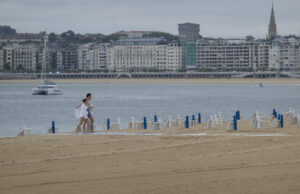 Una pareja sale del agua a primera hora de este lunes en la playa de Ondarreta de San Sebastián. EFE/Javier Etxezarreta