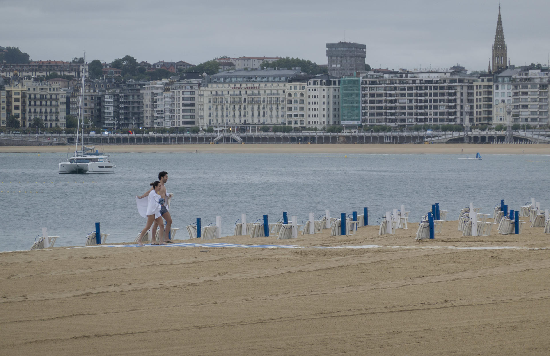 Una pareja sale del agua a primera hora de este lunes en la playa de Ondarreta de San Sebastián. EFE/Javier Etxezarreta