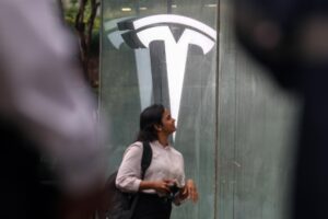 Una mujer camina frente a una sala de exhibición de Tesla. EFE/Divyakant Solanki