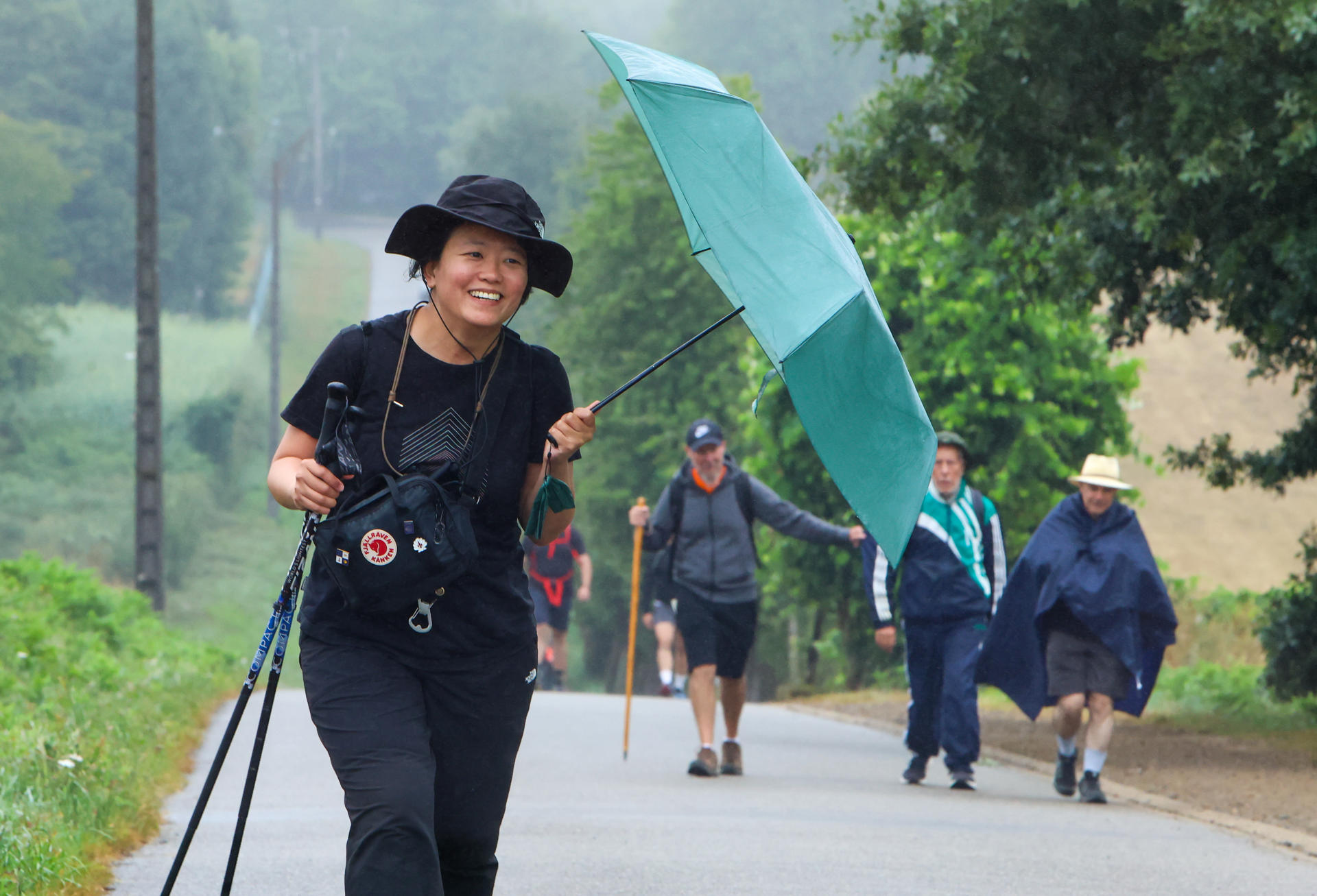 Peregrinos recorren el Camino Francés, protegidos de la lluvia, este viernes antes de su llegada a  Santiago de Compostela. EFE/ Xoán Rey.