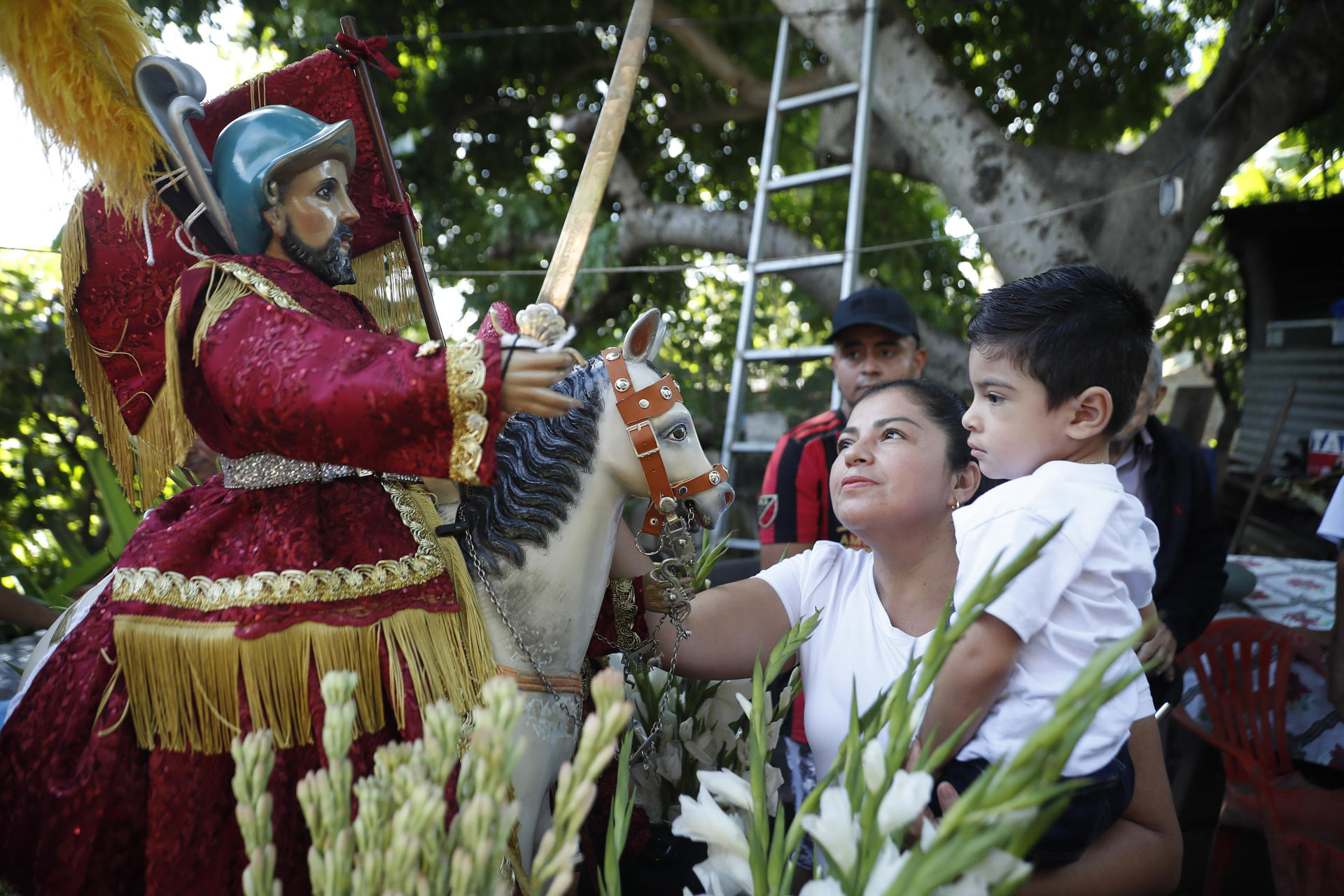 Una mujer y un niño fueron captados este domingo, 6 de julio, al observar la imagen de Santiago Apóstol, durante la procesión de La Demanda, en Apastepeque (El Salvador). EFE/Rodrigo Sura