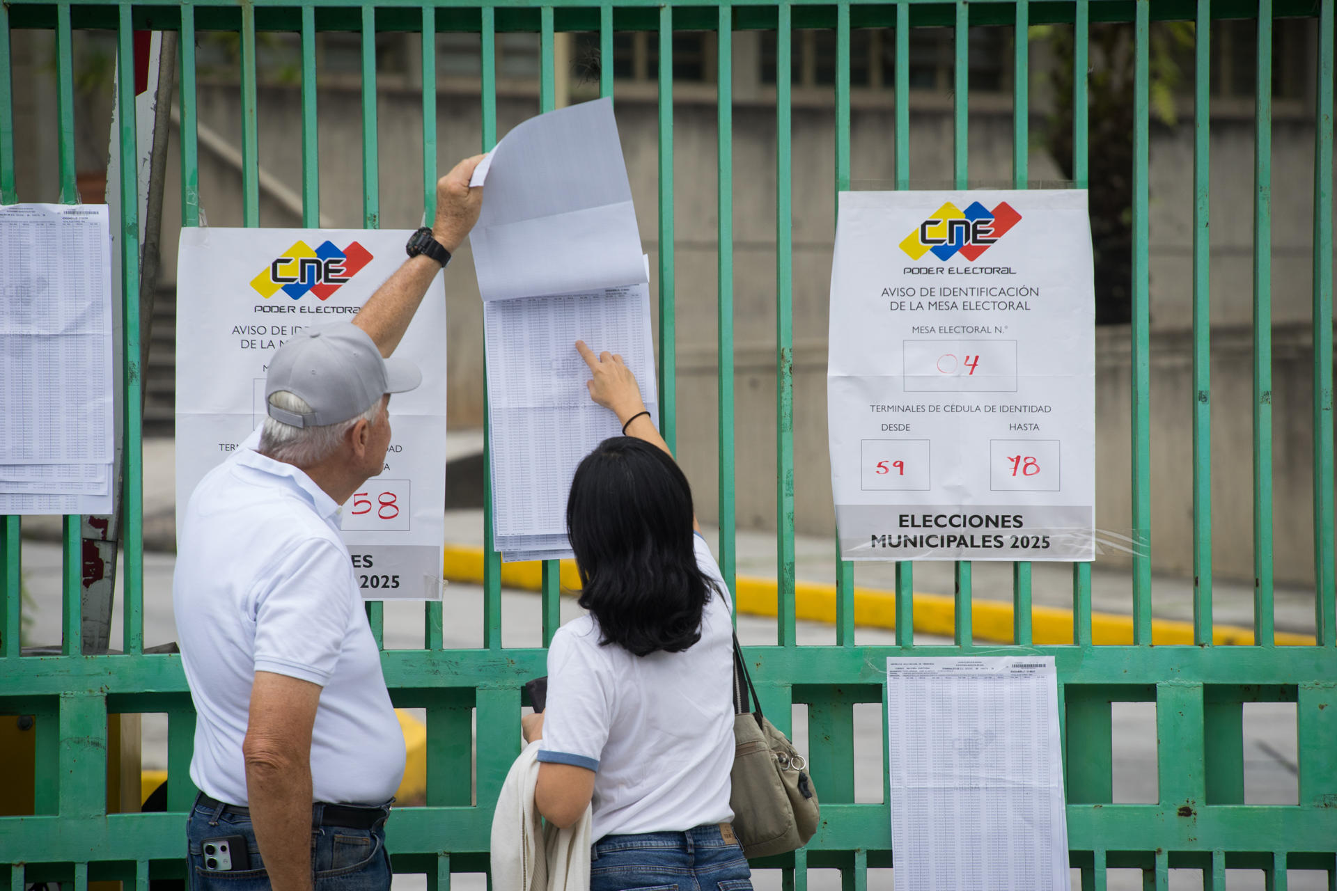 Personas revisan la lista de votación durante las elecciones municipales y concejales este domingo, en Caracas (Venezuela). EFE/ Boris Vergara