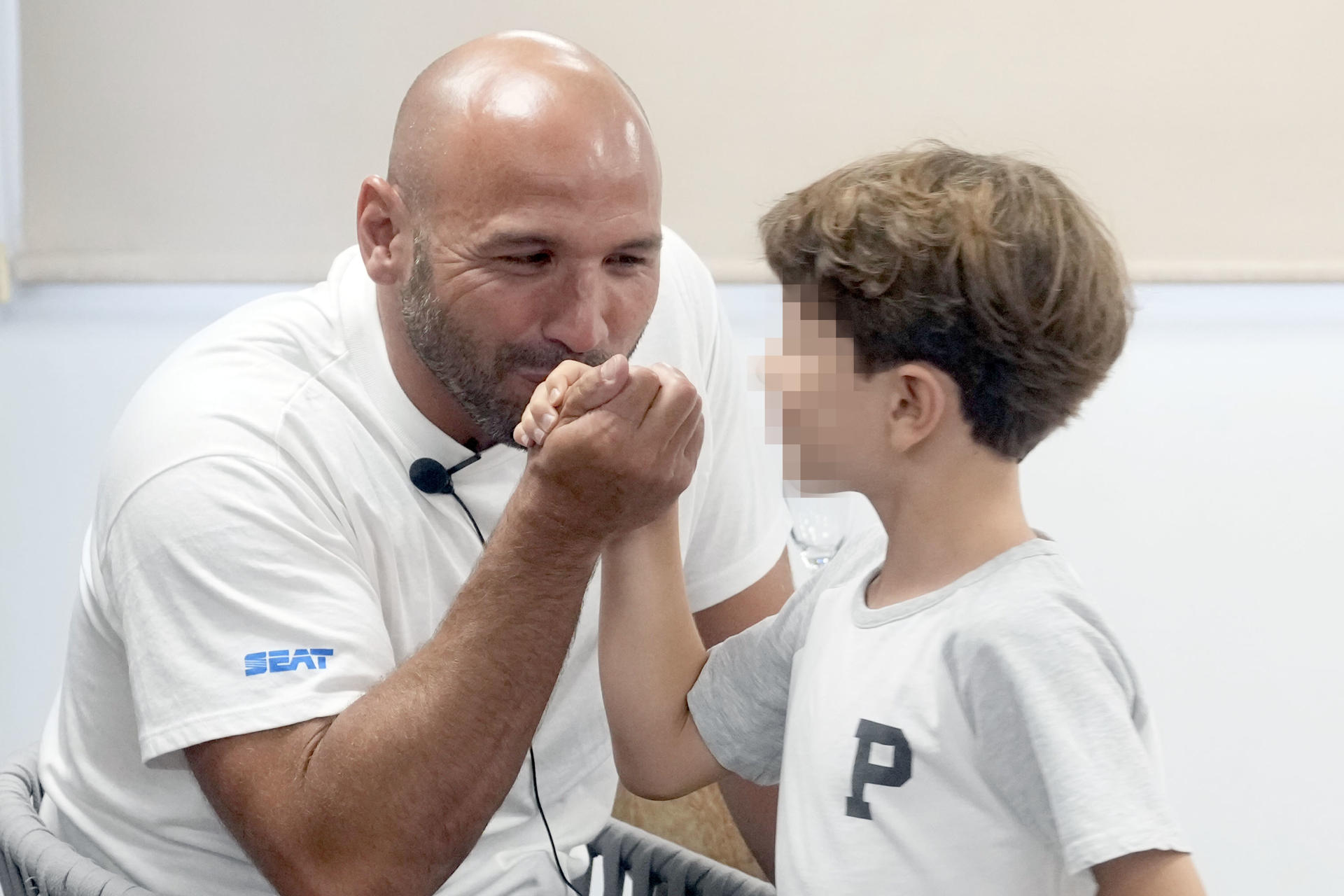 El waterpolista hispano-brasileño Felipe Perrone, capitán de la selección española y uno de los referentes mundiales del waterpolo, saluda a su hijo durante la rueda de prensa que ha ofrecido este martes en Barcelona en la que ha anunciado que abandonará las piscinas tras el Mundial de Natación de Singapur que comienza el próximo día 11 de julio. EFE/Enric Fontcuberta
