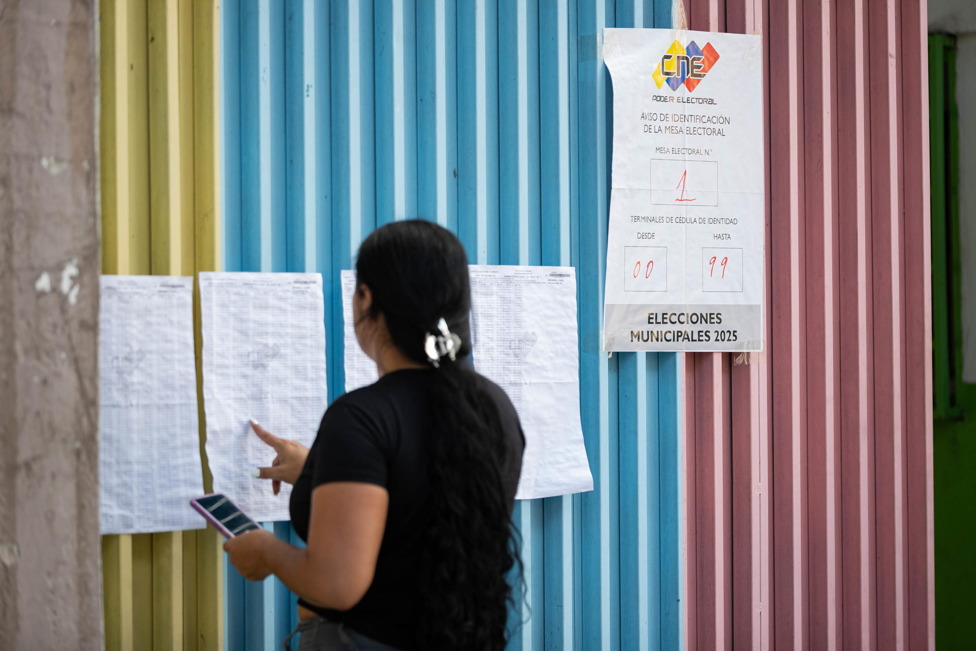 Una persona revisa las listas de las mesas de votación durante las elecciones municipales y concejales este domingo, en Caracas (Venezuela). EFE/ Ronald Peña R