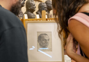Dos personas observan el dibujo de Miguel Hernández (1910-1942) realizado por Antonio Buero Vallejo cuando ambos compartieron celda en la prisión Conde de Toreno de Madrid, poco después de ser condenado a muerte y que el poeta se lo entregó a su esposa, Josefina Manresa, poco antes de morir en la prisión de Alicante. Ese dibujo es una de las joyas del legado hernandiano que la Diputación jiennense adquirió en 2013 a los descendientes del poeta alicantino y que ahora se custodia en sus dos sedes, el Museo Miguel Hernández-Josefina Manresa de Quesada y el Instituto de Estudios Giennenses (IEG), este martes en Jaén. EFE/José Manuel Pedrosa