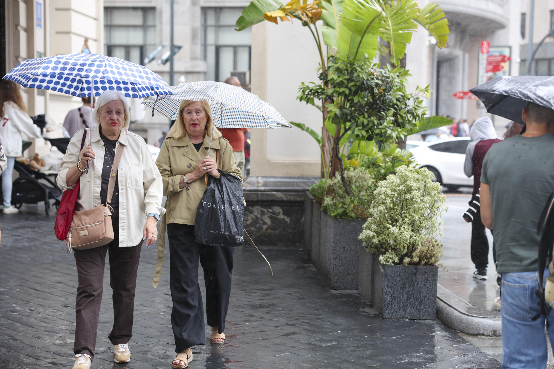 Dos mujeres se protegen del agua con paraguas este lunes en Bilbao. EFE/Luis Tejido