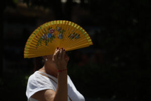 Una mujer se tapa con un abanico mientras camina por el centro histórico de Córdoba, este miércoles. EFE/Salas