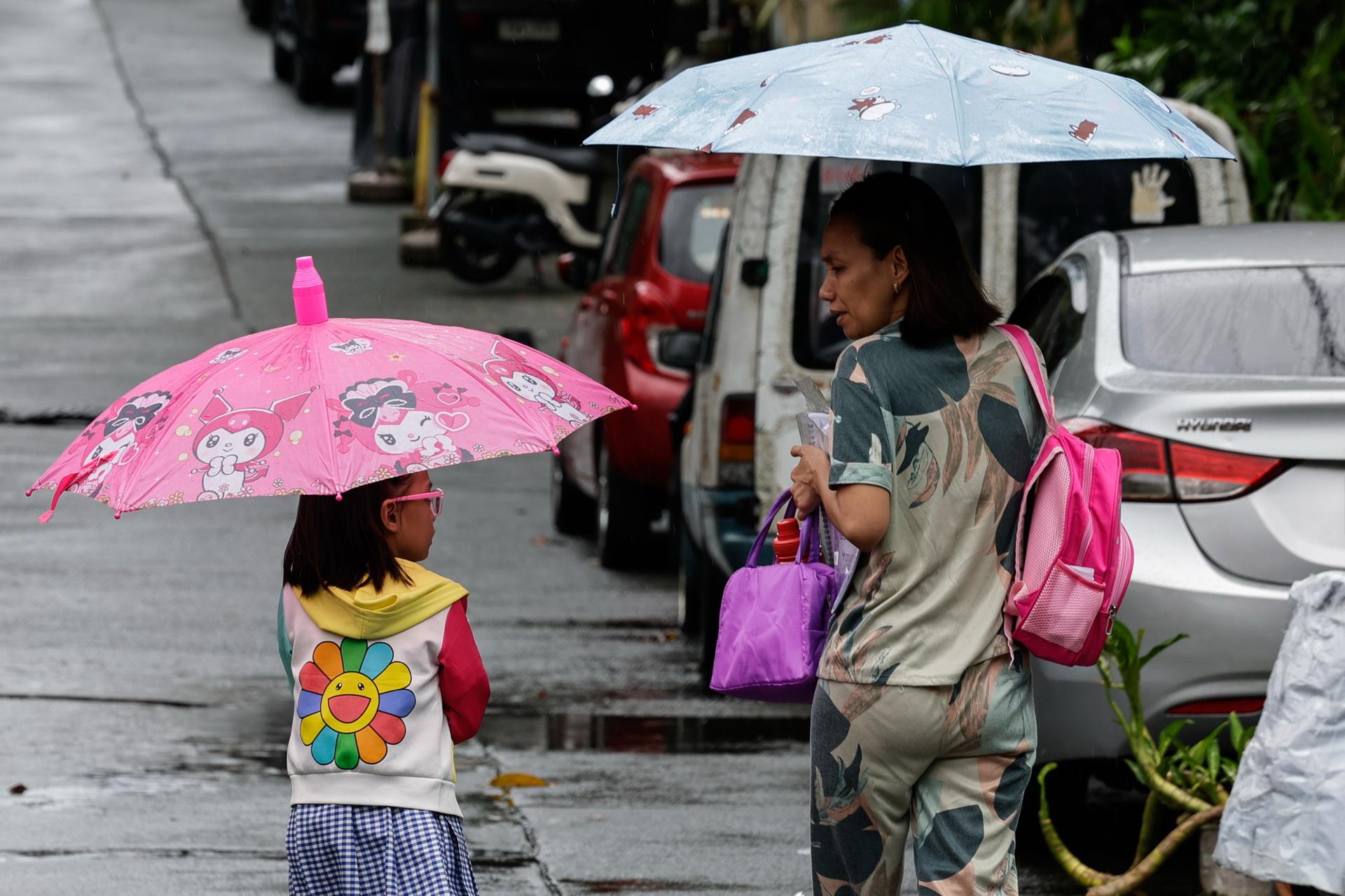 CIUDAD QUEZÓN (Filipinas), 03/07/2025.- Una madre camina con su hija frente a una escuela primaria pública tras la suspensión de clases en Ciudad Quezón, Metro Manila, Filipinas, el 3 de julio de 2025, debido a las fuertes lluvias asociadas a la depresión tropical Bising, que se espera produzca inundaciones y deslizamientos de tierra mientras toma fuerza y se desplaza hacia el mar al sur de Taiwán. EFE/EPA/ROLEX DELA PENA