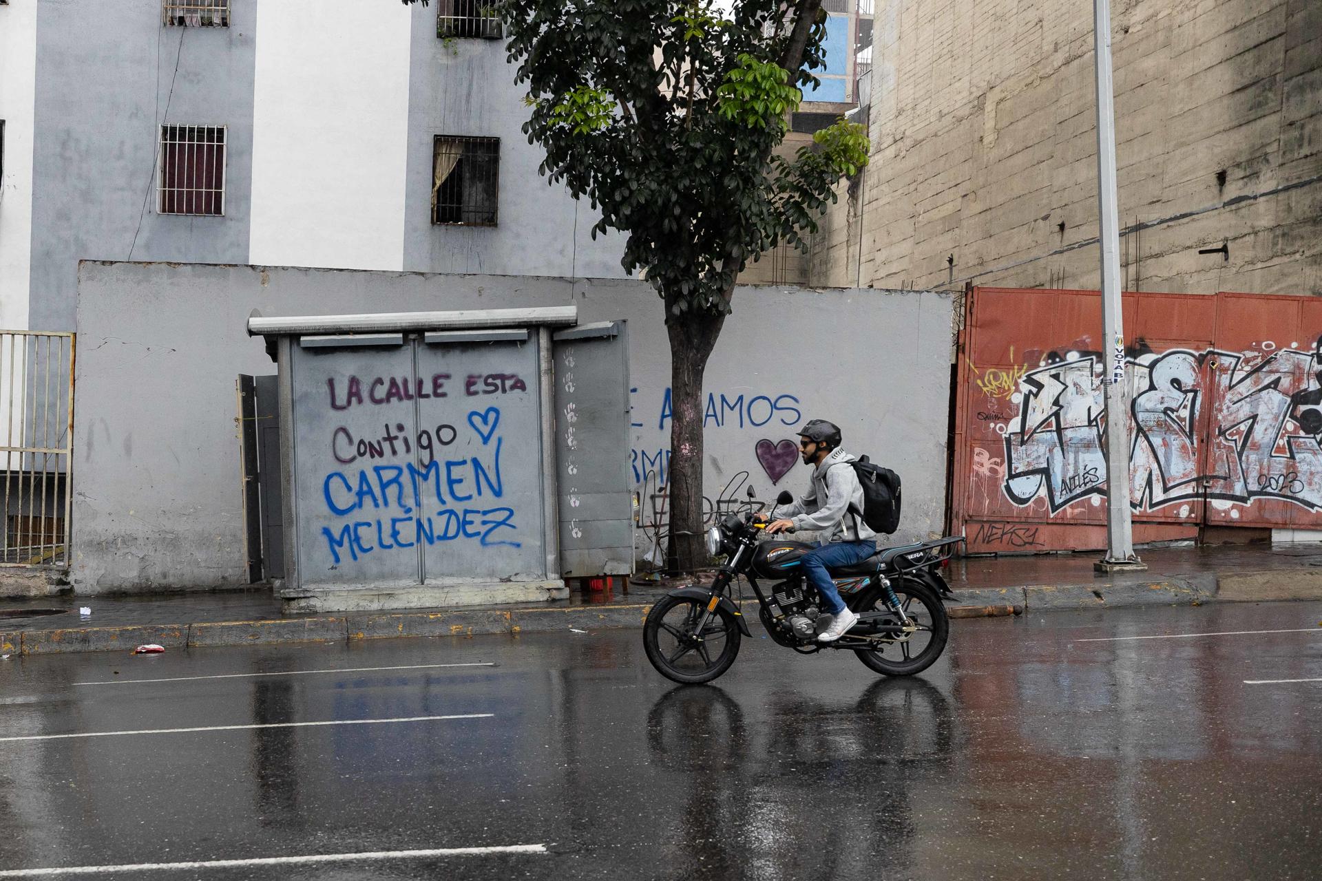 Una persona en motocicleta pasa frente a un grafiti de la alcaldesa del municipio Libertador de Caracas, Carmen Melénez, este sábado en Caracas (Venezuela). EFE/ Ronald Peña R