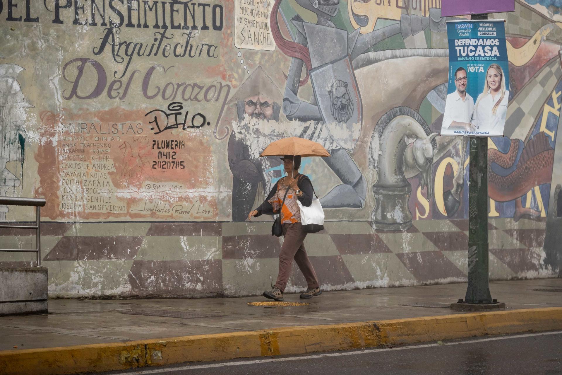 Un mujer camina frente a un valla del alcalde del municipio Baruta de Caracas, Darwin González, este sábado en Caracas (Venezuela). EFE/ Ronald Peña R