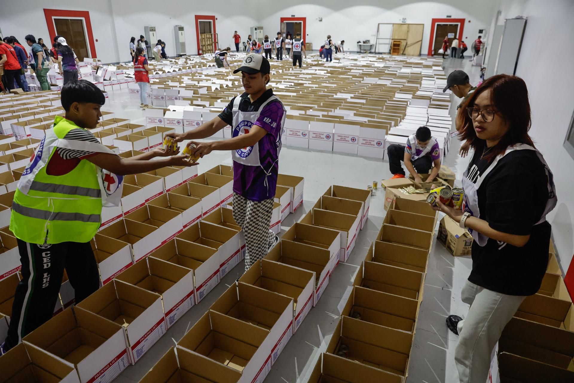 MANDALUYONG (Philippines), 24/07/2025.- Volunteers for the Philippine Red Cross fill care packages with food items for distribution in flood affected areas, from their headquarters in Mandaluyong City, Metro Manila, Philippines, 24 July 2025. The Philippines weather bureau projected typhoon Co-May to be 210 kilometers west of Pangasinan province in the northern Philippines, with winds of 120 kilometers per hour near its center. (Filipinas) EFE/EPA/ROLEX DELA PENA
