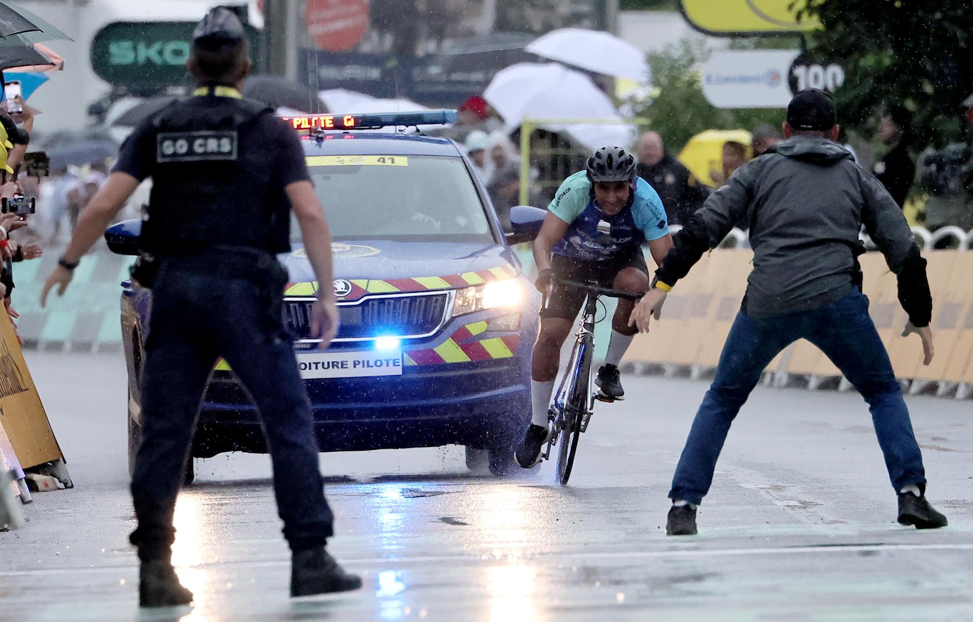 Personal de seguridad se prepara para detener a un aficionado en bicicleta antes de la meta, en la 17ª etapa del Tour de Francia, disputada este miércoles, en Valence (Francia). EFE/Christophe Petit Tesson