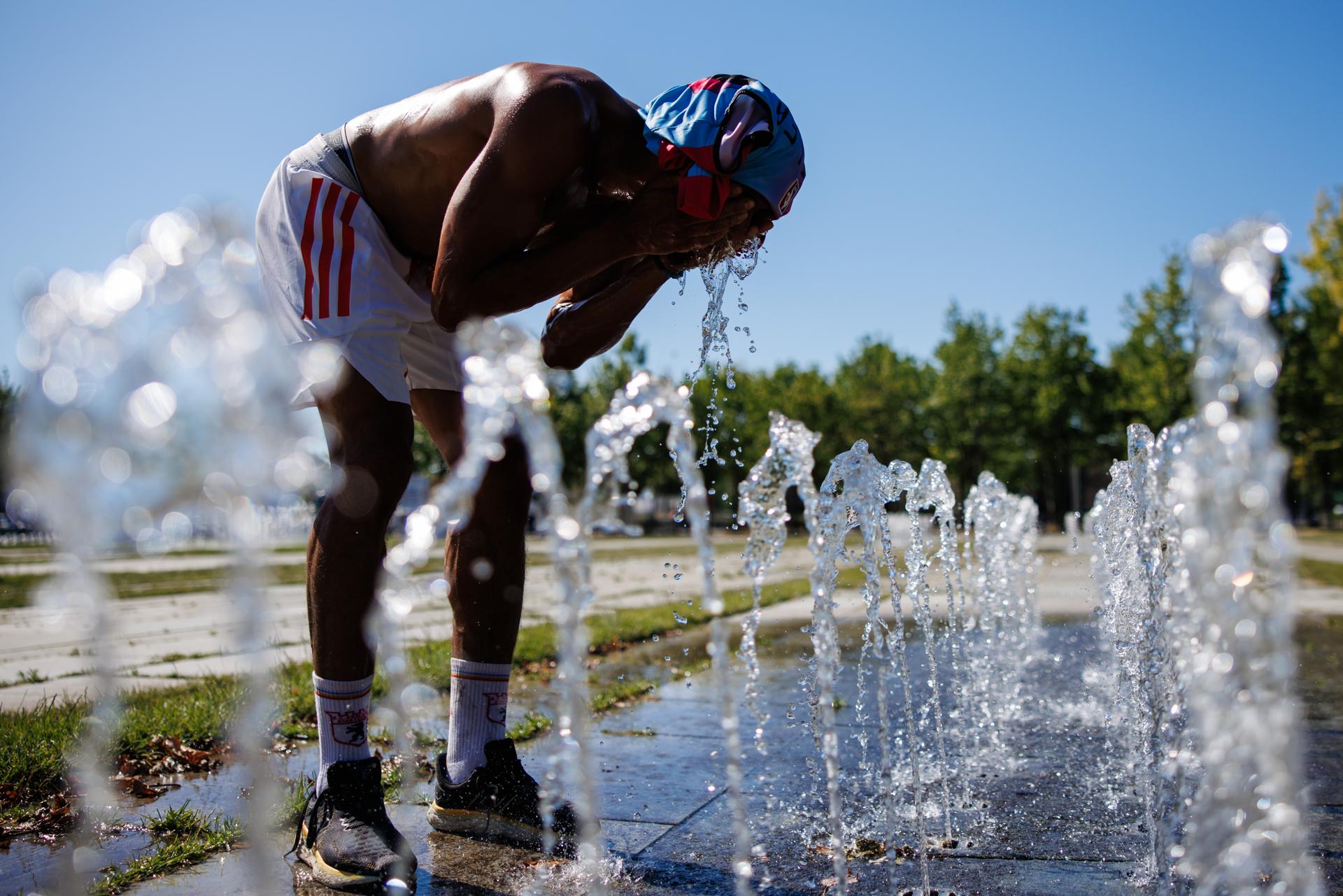 Un peatón en una fuente pública se vierte agua en la cara en un día caluroso en Berlín, Alemania, este miércoles. EFE/ Clemens Bilan
