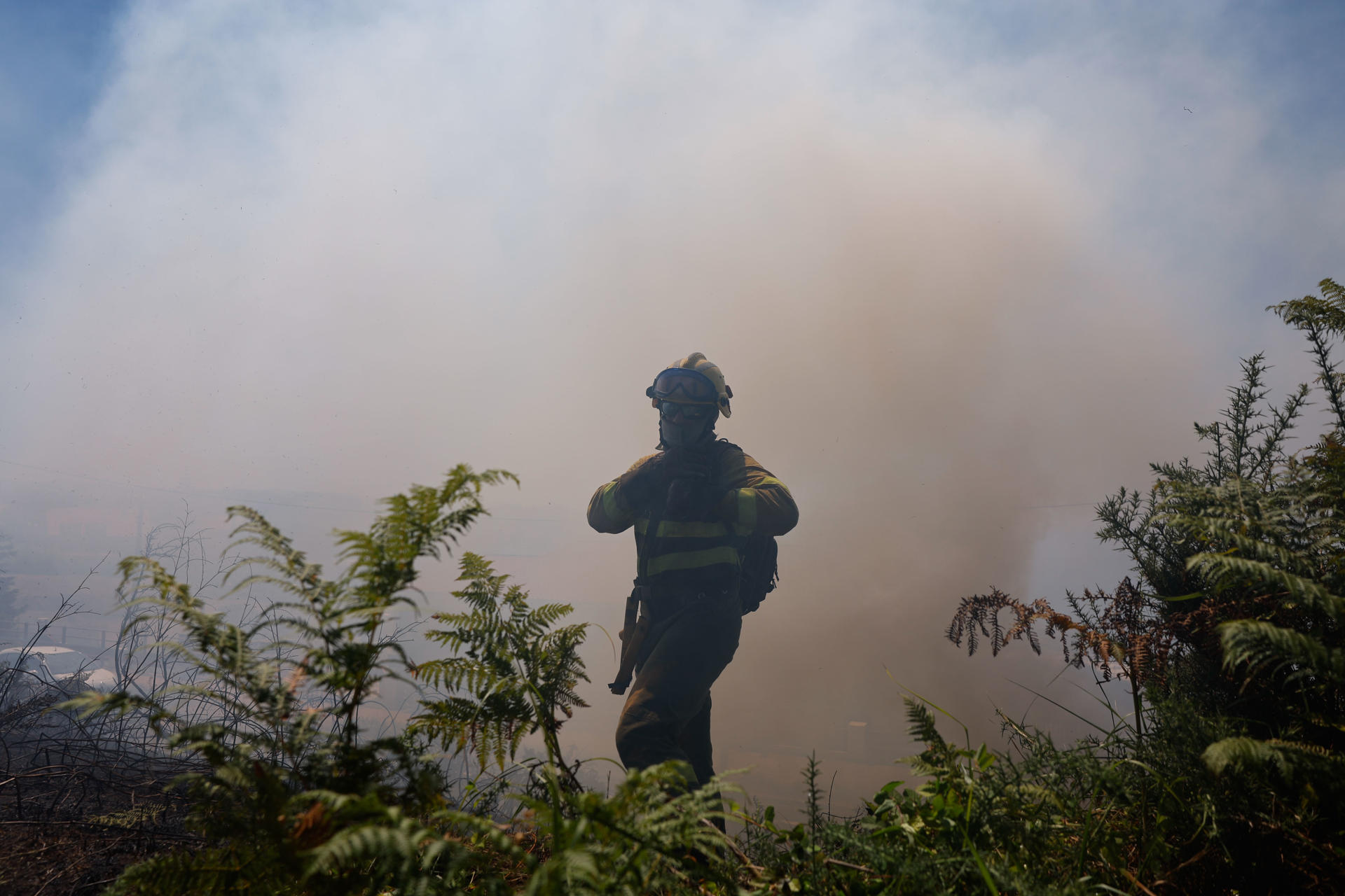 Bomberos trabajan este martes, en la extinción de un incendio en A Lanzada (Pontevedra). EFE/ Lavandeira Jr