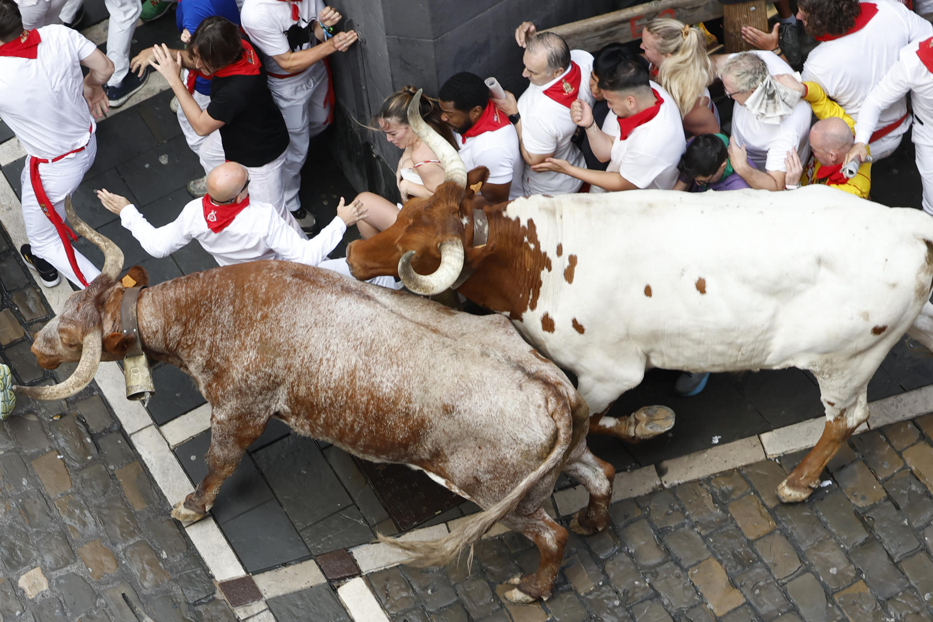 Los mozos se arrinconan en una esquina al paso de los toros de la ganadería gaditana de Fuente Ymbro durante el primer encierro de los Sanfermines 2025, este lunes en Pamplona. EFE/Jesús Diges