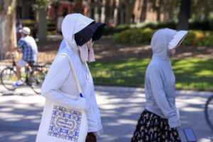 Dos turistas se protegen del sol en los alrededores del Palacio Real este martes en Madrid. El calor será intenso desde este martes en casi todo el territorio debido a la presencia de una masa de aire muy cálido que dará un alivio entre el viernes y el sábado, pero que repuntará el domingo, con temperaturas significativamente altas hoy en el centro y mitad sur peninsular así como en Canarias. EFE/ Pablo R. Seco