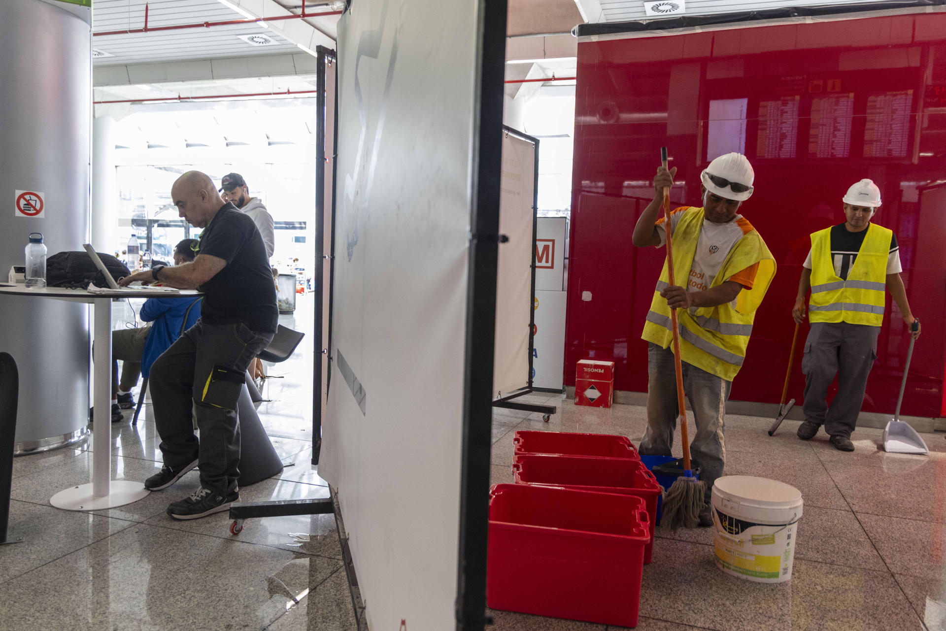 Varios operarios limpian el agua que inunda el aeropuerto de Palma a causa de las goteras provocadas por las intensas lluvias de este jueves. EFE/ Cati Cladera