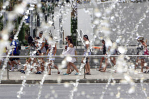 Varias personas pasan ante una fuente, este jueves, en una calle de la ciudad de Alicante. EFE/Pep Morell