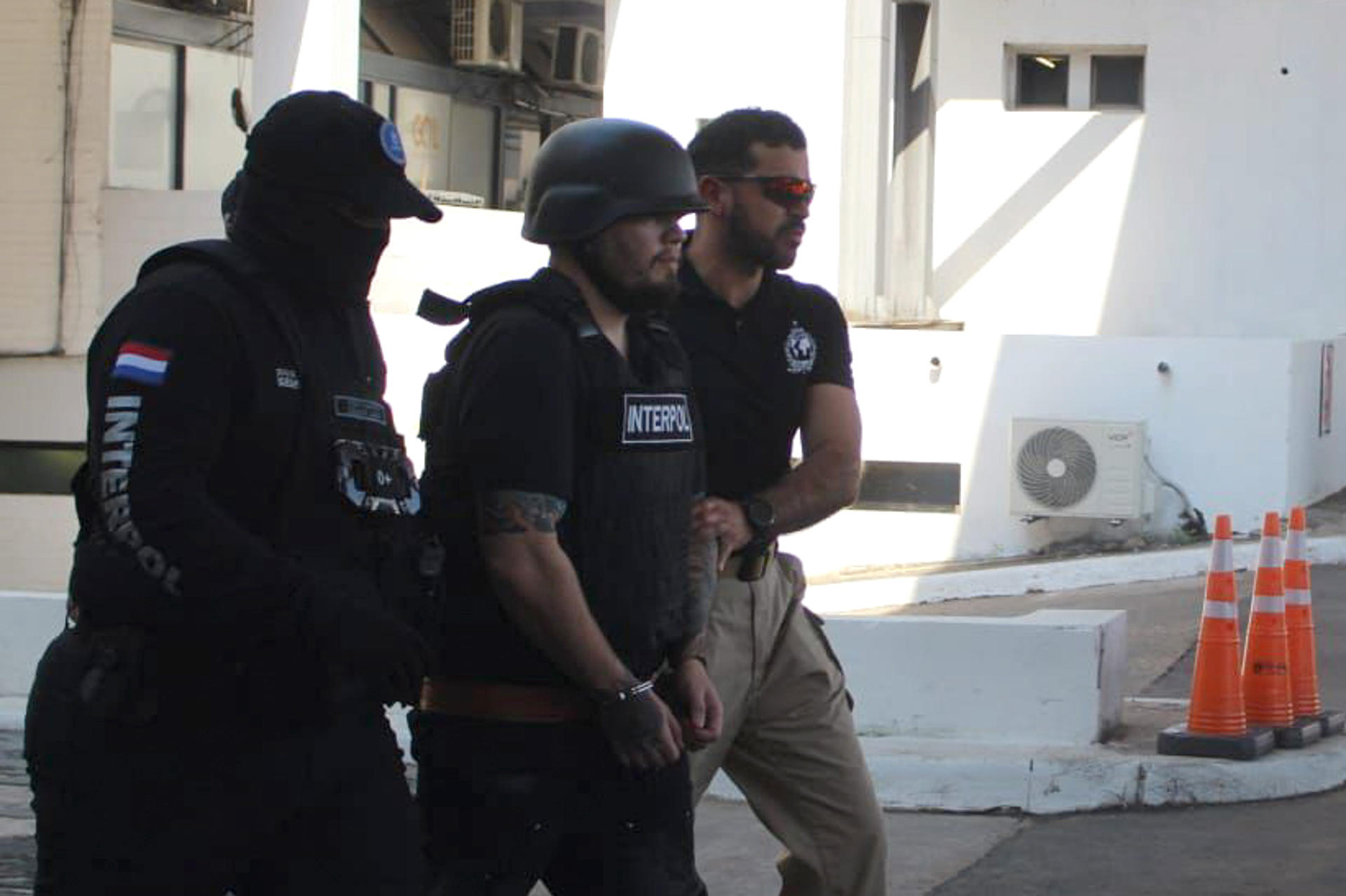 Fotografía cedida por Interpol Paraguay donde se observa a integrantes de esa entidad trasladando al ciudadano paraguayo José Estigarribia Cristaldo, alias La Maldad, deportado desde Emiratos Árabes Unidos, este sábado en el Aeropuerto Internacional Silvio Pettirossi, en Luque (Paraguay). EFE/ Interpol Paraguay