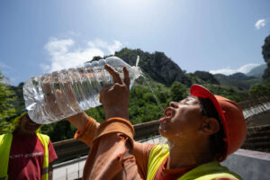 Un trabajador se refresca este martes en el desfiladero de La Hermida, en una jornada en la que Liébana (Cantabria) se encuentra en aviso naranja por temperaturas de hasta 37 grados. EFE/ Pedro Puente Hoyos