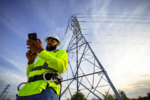 Fotografía edida por T-Mobile que muestra a una persona observando su teléfono frente a una torre eléctrica en Estados Unidos. EFE/ T-mobile