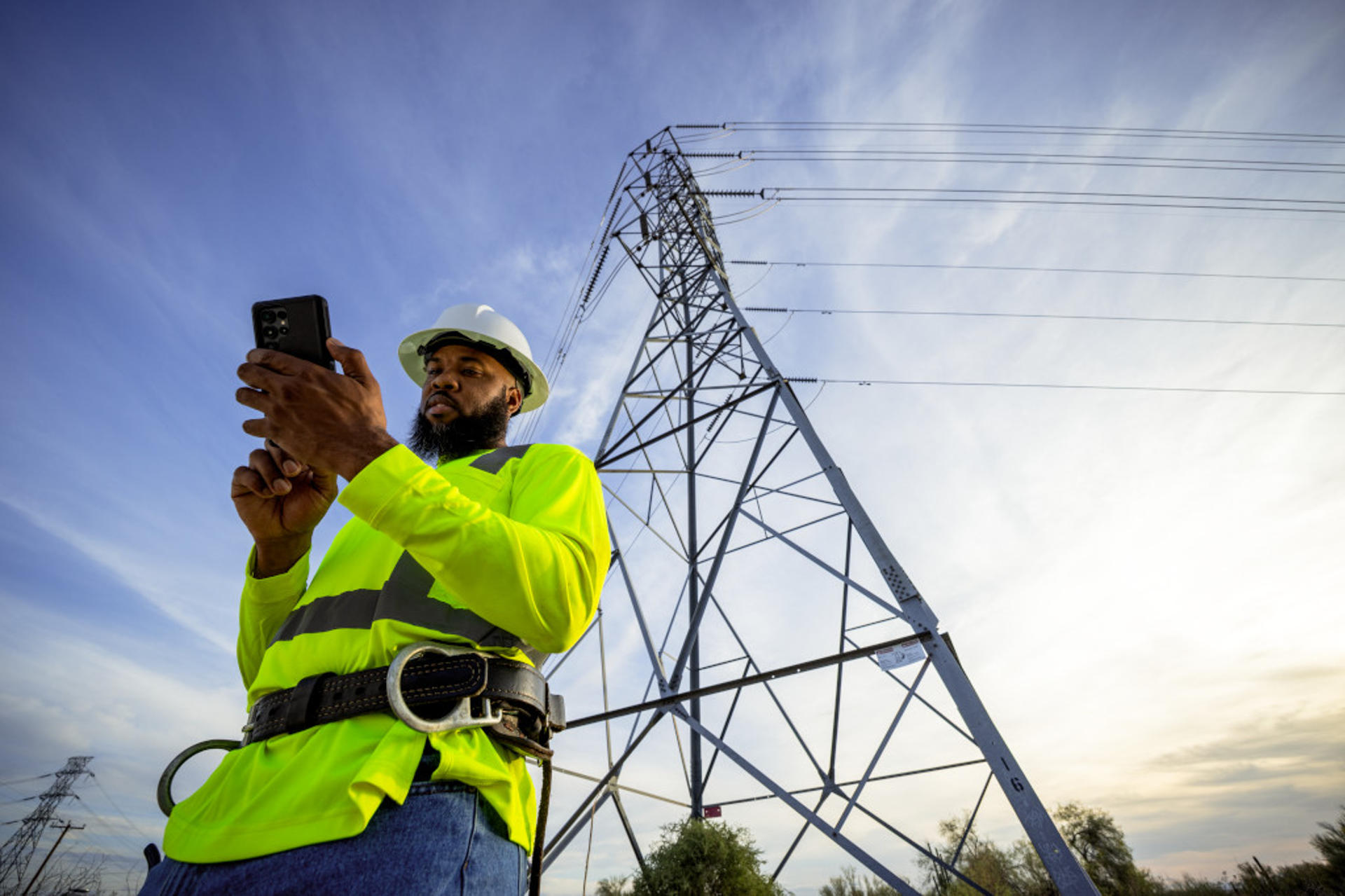 Fotografía edida por T-Mobile que muestra a una persona observando su teléfono frente a una torre eléctrica en Estados Unidos. EFE/ T-mobile