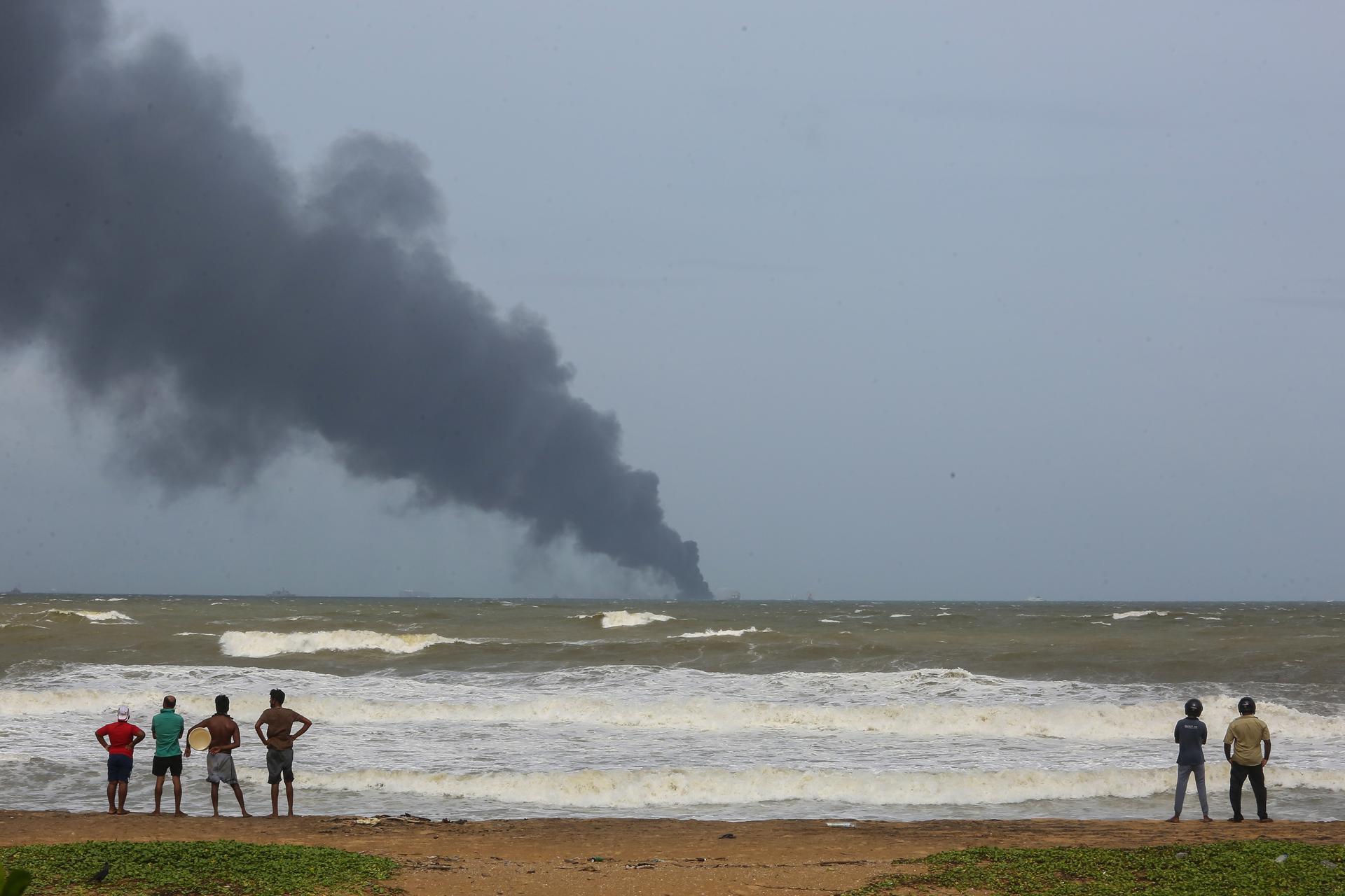 Fotografía de archivo de personas observando el humo del buque X-Press Pearl en llamas, al noroeste de Colombo, Sri Lanka, en mayo de 2021. EFE