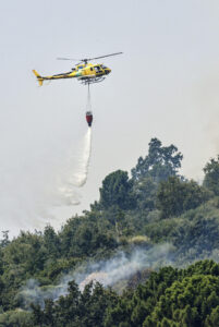 Un helicóptero trabaja en las labores de extinción del incendio en Mombeltrán (Ávila). La Junta de Castilla y León ha puesto fin al confinamiento decretado en los municipios abulenses de Mombeltrán y El Arenal por el humo y las cenizas del incendio que afecta a esta zona del sur de Ávila que, si bien se mantiene activo con unas 2.000 hectáreas ya quemadas, su evolución es favorable. Esta medida ha afectado a cerca de 4.000 personas que durante estos días estivales se encuentran en estas dos localidades que entre las dos no llegan a 2.000 habitantes censados.-EFE/ Raúl Sanchidrián