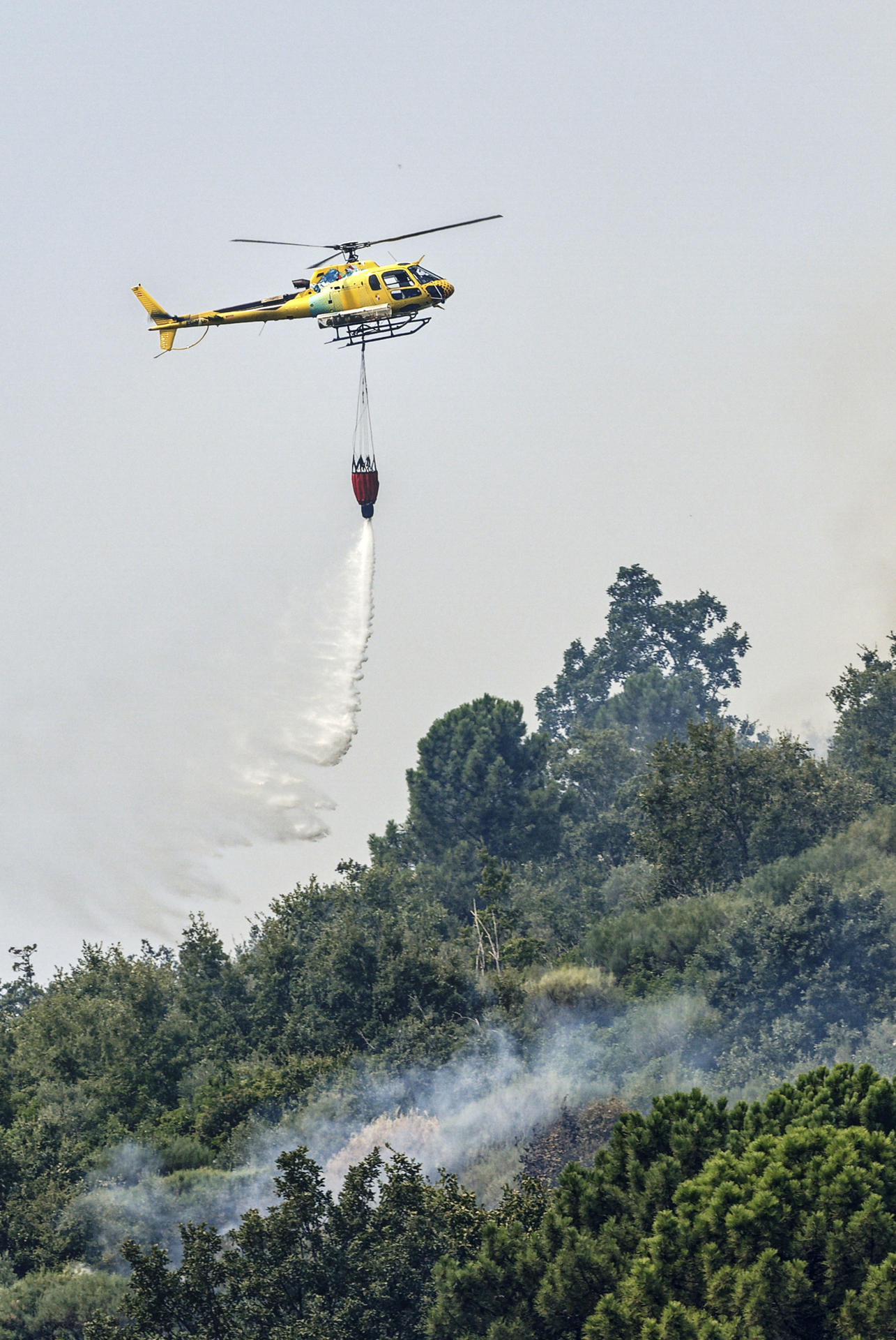 Un helicóptero trabaja en las labores de extinción del incendio en Mombeltrán (Ávila). La Junta de Castilla y León ha puesto fin al confinamiento decretado en los municipios abulenses de Mombeltrán y El Arenal por el humo y las cenizas del incendio que afecta a esta zona del sur de Ávila que, si bien se mantiene activo con unas 2.000 hectáreas ya quemadas, su evolución es favorable. Esta medida ha afectado a cerca de 4.000 personas que durante estos días estivales se encuentran en estas dos localidades que entre las dos no llegan a 2.000 habitantes censados.-EFE/ Raúl Sanchidrián