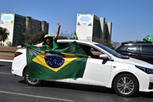 Una simpatizante del expresidente de Brasil, Jair Bolsonaro, sostiene una bandera durante una caravana este domingo, en la Explanada de los Ministerios en Brasilia (Brasil). EFE/ Andre Borges