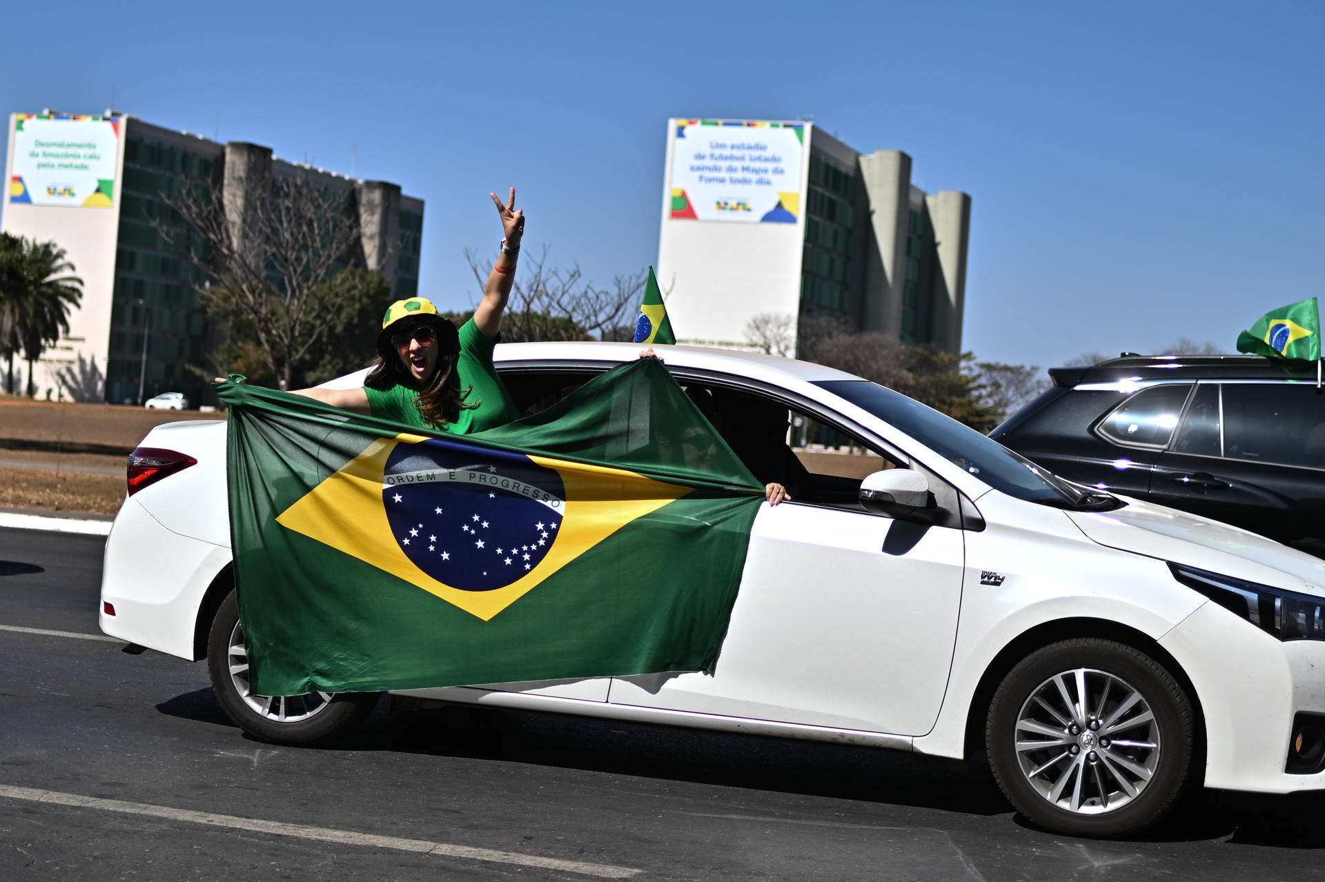 Una simpatizante del expresidente de Brasil, Jair Bolsonaro, sostiene una bandera durante una caravana este domingo, en la Explanada de los Ministerios en Brasilia (Brasil). EFE/ Andre Borges