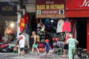 HANÓI (Vietnam), 03/07/2025.- Turistas pasan frente a una tienda con un rótulo en el que puede leerse "Hecho en Vietnam" en una calle de Hanói, Vietnam, el 3 de julio de 2025. EFE/EPA/LUONG THAI LINH