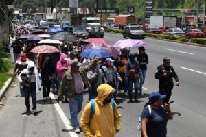 Personas caminan sobre una vía desbloqueda por integrantes de la Policía Nacional Civil durante una manifestación del Sindicato de Trabajadores de la Educación en Guatemala (STEG) este lunes, en Ciudad de Guatemala (Guatemala). EFE/ Alex Caña