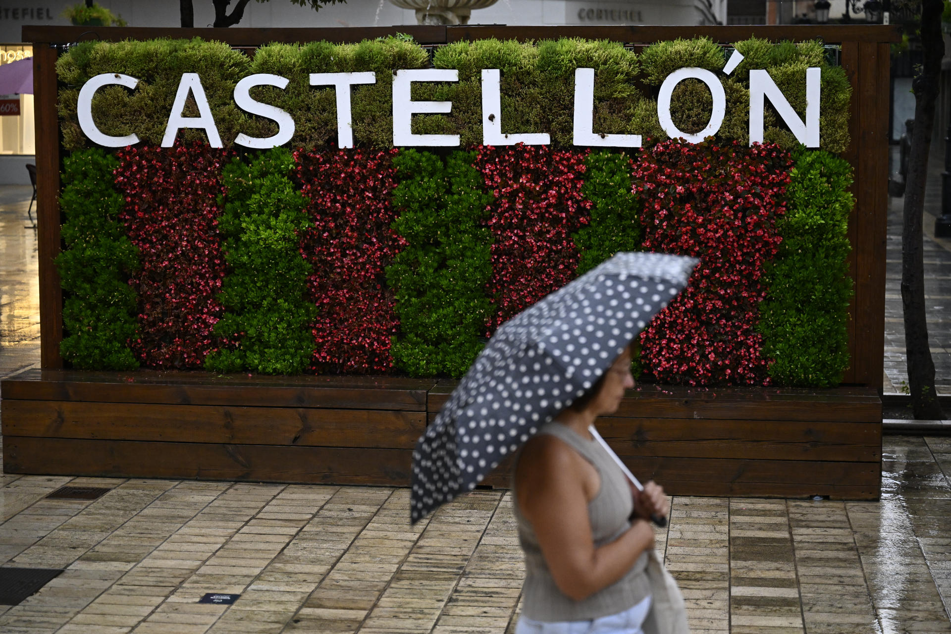 Una mujer cruza, este miércoles, por una calle de la ciudad de Castellón bajo una intensa lluvia. EFE/Andreu Esteban