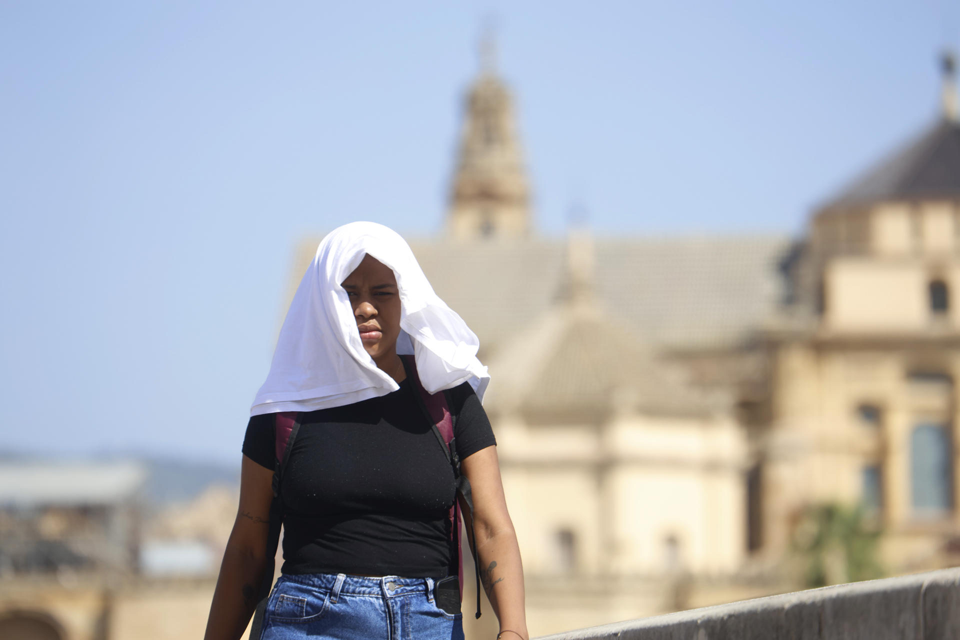 Una mujer se tapa con una camiseta mientras camina por el Puente Romano de Córdoba, este miércoles. EFE/Salas