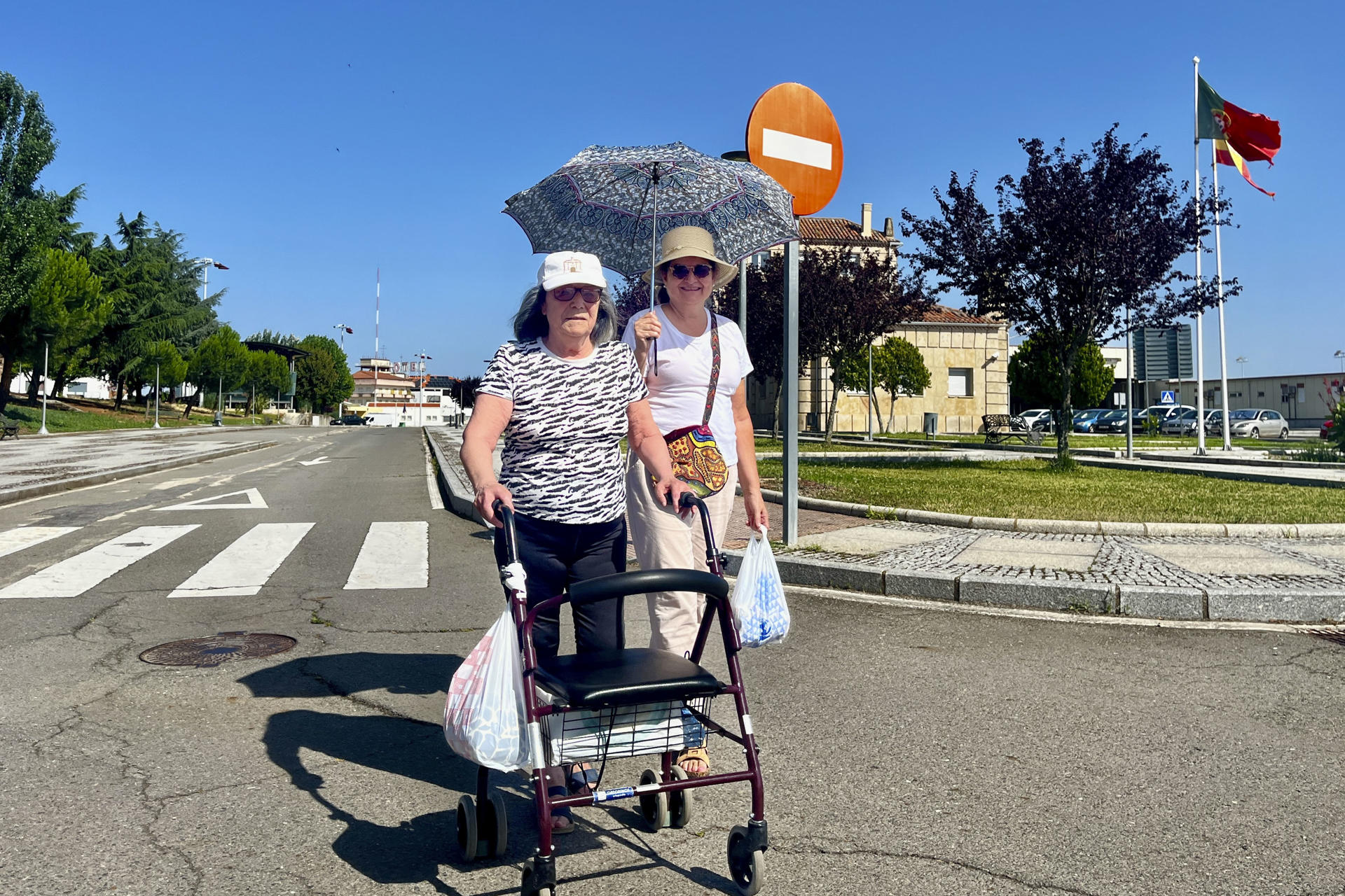 Dos mujeres pasean con el paraguas en la localidad portuguesa de Vilar Formoso (Portugal), para protegerse del sol. Los distritos del norte y centro de Portugal limítrofes con España se encuentran este martes en el nivel de "peligro máximo" (el más alto) de incendio forestal, debido a las condiciones climatológicas, especialmente por las altas temperaturas y la humedad relativa. EFE/ Carlos García.