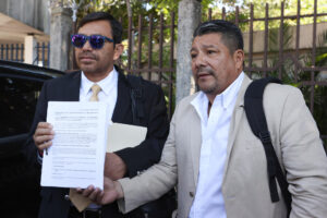 Los integrantes del Movimiento para la Defensa de la Clase Trabajadora (MDCT), el abogado Luis Rivera (i) y Guillermo García, muestran un documento afuera de la Sala de lo Constitucional de la Corte Suprema de Justicia (CSJ) este jueves, en San Salvador (El Salvador). EFE/ Javier Aparicio