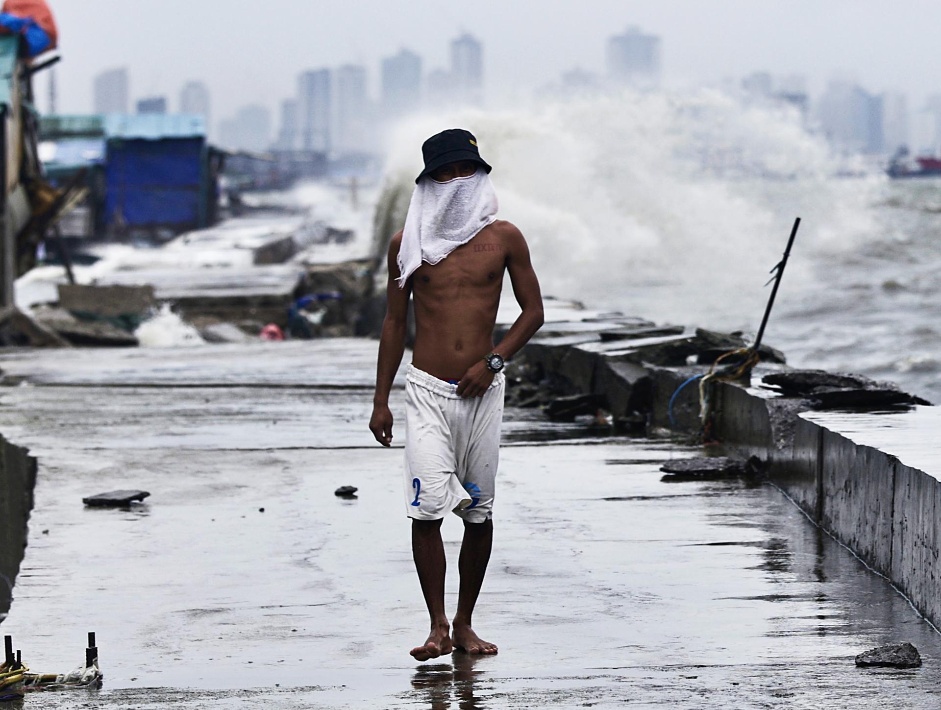 Una persona camina junto a un dique dañado por la fuerza del viento en la ciudad de Navotas, en Filipinas. EFE/EPA/FRANCIS R. MALASIG