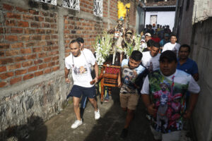 Un grupo de hombres fue captado este domingo, 6 de julio, al correr con la imagen de Santiago Apóstol, durante la procesión de La Demanda, en Apastepeque (El Salvador). EFE/Rodrigo Sura