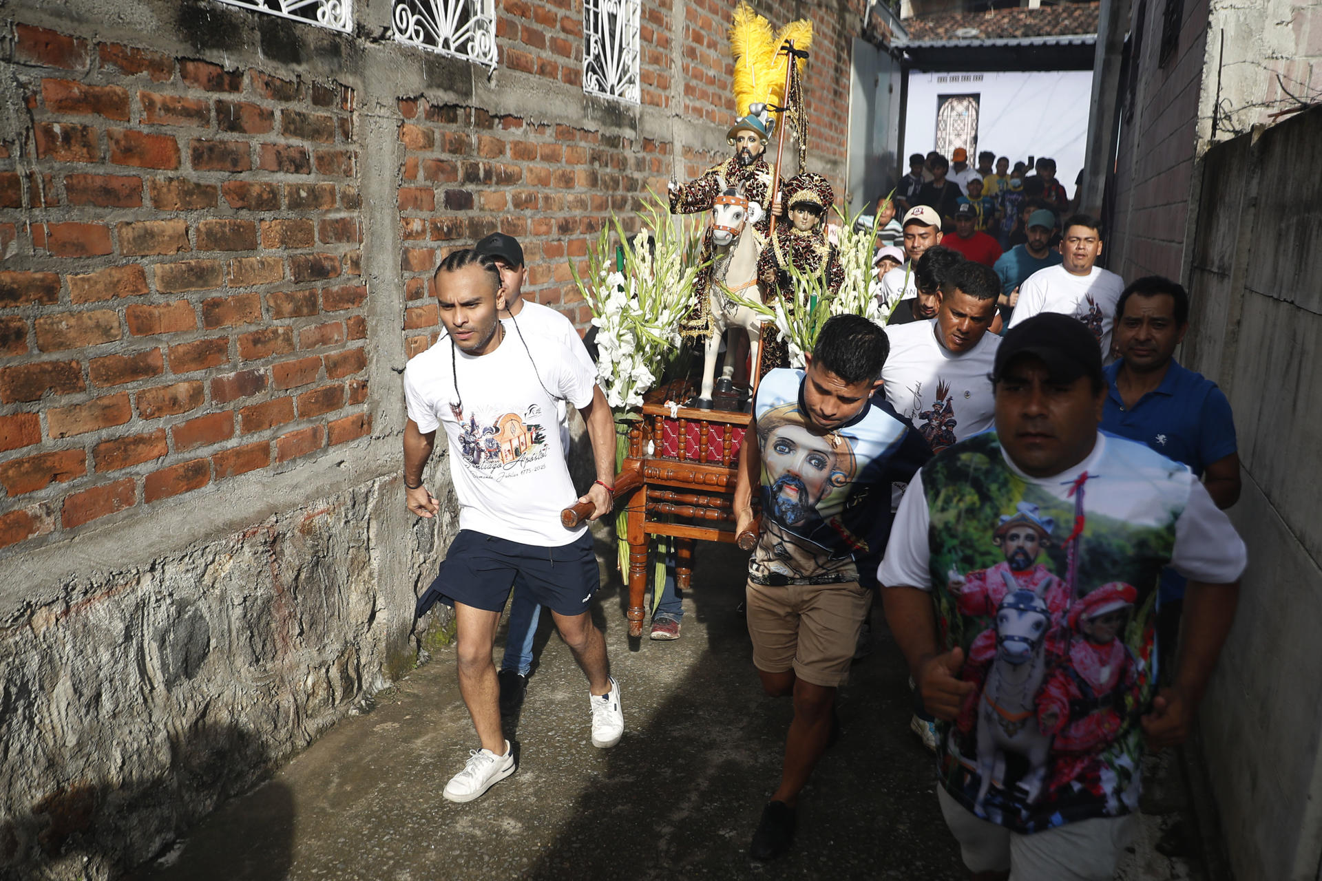 Un grupo de hombres fue captado este domingo, 6 de julio, al correr con la imagen de Santiago Apóstol, durante la procesión de La Demanda, en Apastepeque (El Salvador). EFE/Rodrigo Sura