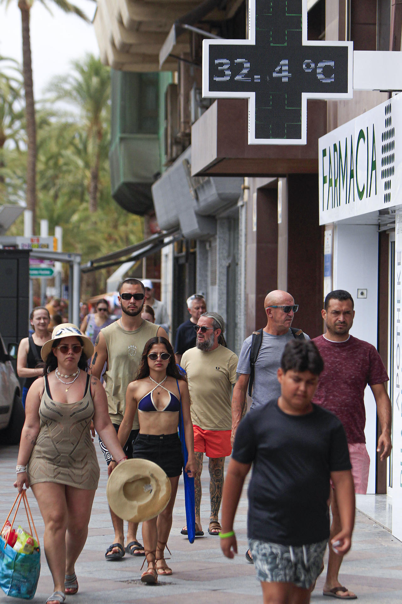 Varias personas pasan ante un termómetro urbano, este jueves, cercano a la playa alicantina de El Postiguet, Alicante. EFE/Pep Morell