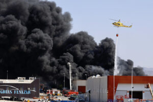 Bomberos y medios aéreos trabajan para extinguir un incendio en una nave de reciclaje de plásticos del polígono industrial de Fortuna (Murcia), que se declaró sobre las 09:00 horas y ha generado una densa nube negra con posible toxicidad. Protección Civil ha activado un aviso a la población y ha recomendado el confinamiento inmediato de viviendas cercanas, instando a cerrar puertas y ventanas y no salir al exterior. EFE/Juan Carlos Caval