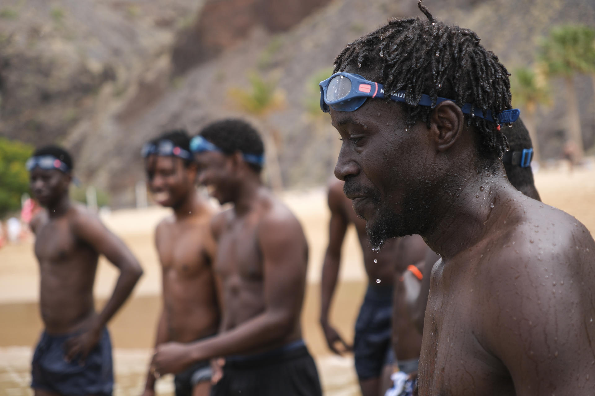 Imagen de archivo (07/07/2025) de un grupo de jóvenes inmigrantes llegados a Canarias en cayuco desde distintos puntos de África en una de las sesiones del 'Proyecto Agua' en la playa de Las Teresitas, en Santa Cruz de Tenerife, una iniciativa llevaba a cabo por las ONG Promeaid y Accem que busca enseñarles a nadar y a reconciliarse con el mar después de una experiencia traumática. EFE/Alberto Valdés
