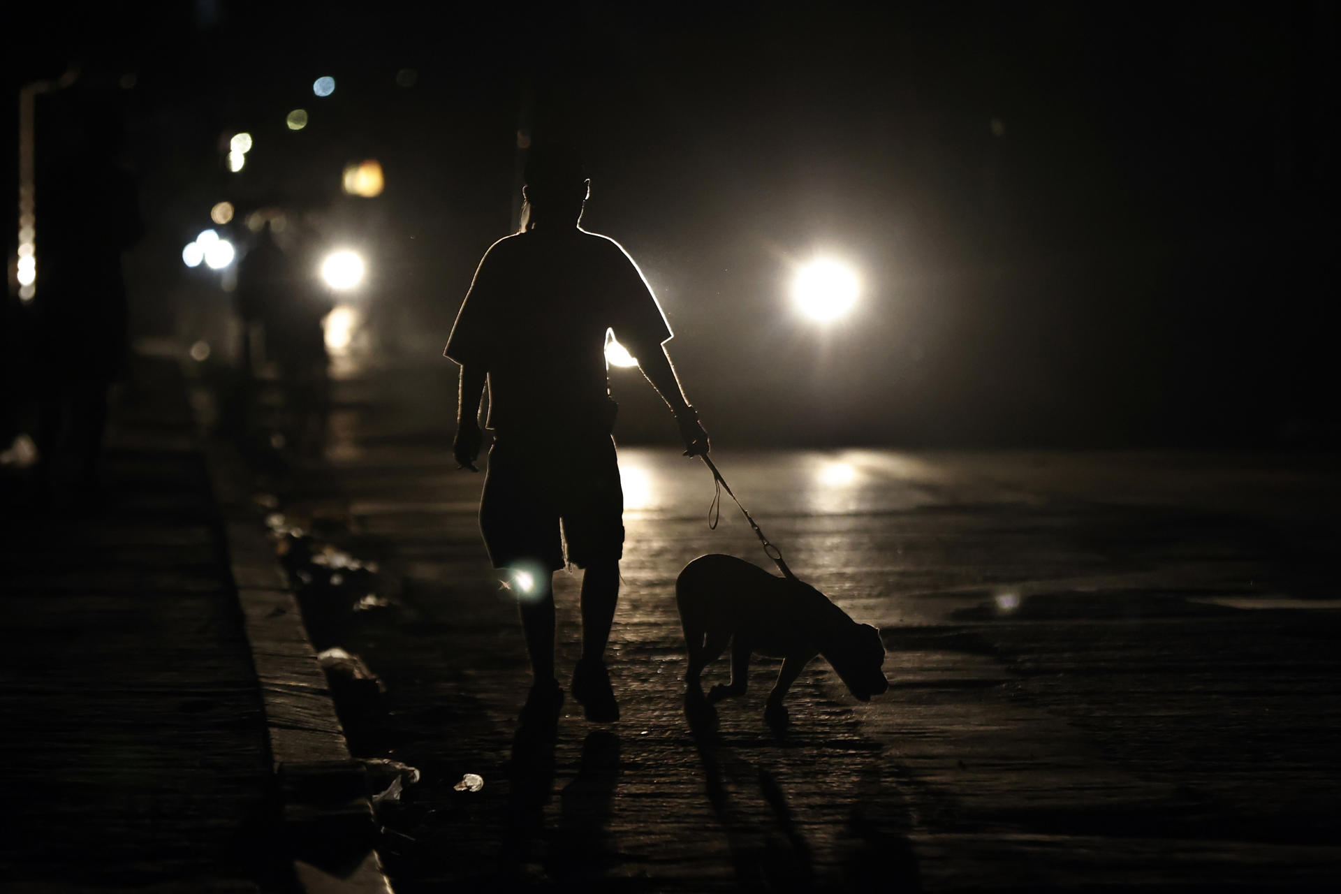 Una persona fue captada en la madrugada de este 1 de julio al pasear con su perro por una calle de La Habana, durante uno de los diarios apagones eléctricos en Cuba. EFE/Ernesto Mastrascusa